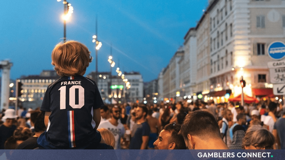 A child wearing a France football kit among thousands of fans celebrating in a crowded city street, symbolizing nationwide support during the tournament.