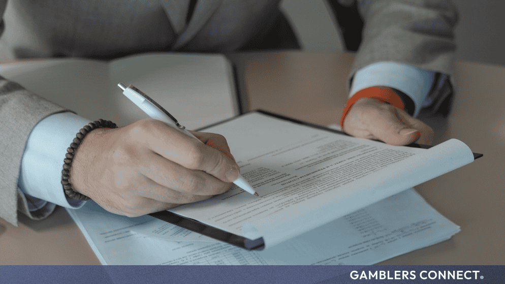 Ireland and Denmark Sign Memorandum of Understanding to Align Gambling Regulation 1 Close-up view of hands holding and signing a corporate compliance contract, symbolizing the alignment of international regulatory protocols.