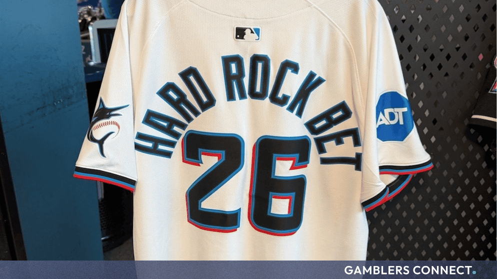 A white baseball jersey displaying "Hard Rock Bet" and the number 26 on the back, representing the brand's sports sponsorships and expansion.