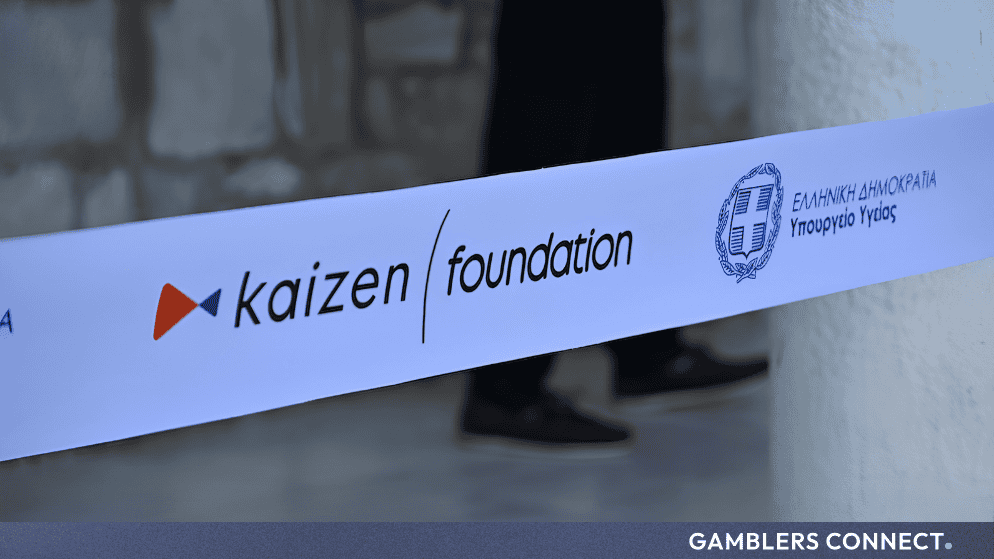 Close-up of the Kaizen Foundation branding on a white ribbon alongside official Greek government emblems.