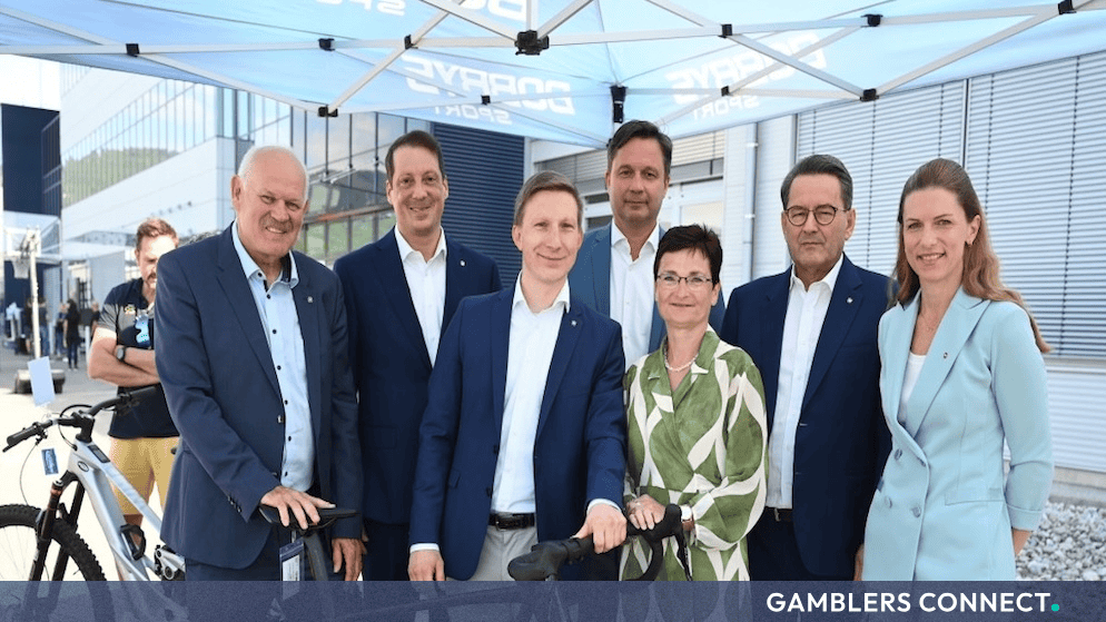 The NOVOMATIC corporate management team posing with e-bikes under a branded tent at the company's Gumpoldskirchen headquarters.