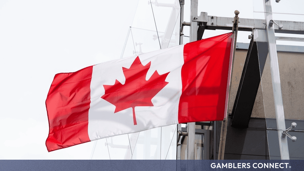 AGCO Proposes 60-Day Liquor Licence Suspension for Hamilton Venue Following Over-Service Investigation 1 A close-up side view of the Canadian flag waving beside a transparent glass architectural facade, representing federal and provincial regulatory compliance.