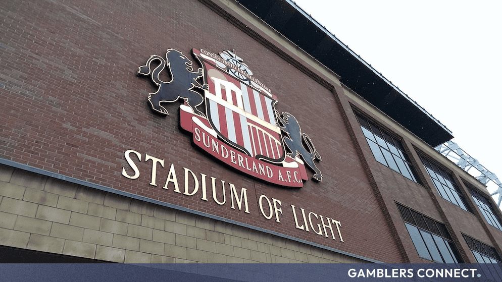 The exterior brick wall of Sunderland's Stadium of Light featuring the club crest and gold lettering.