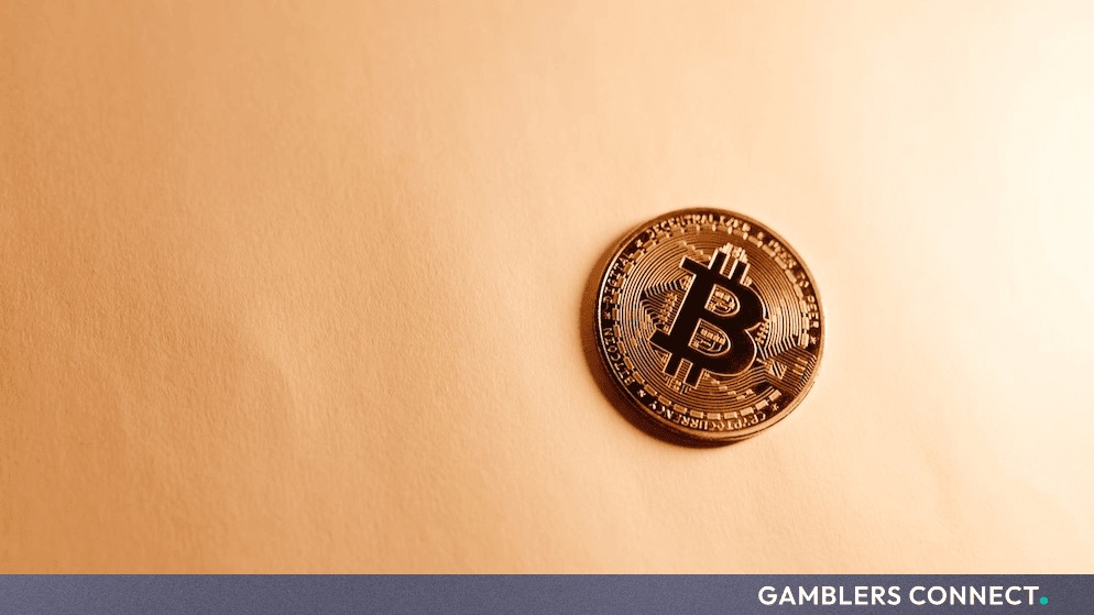 A physical Bitcoin token resting on a clean golden-toned surface representing cryptocurrency market movements.