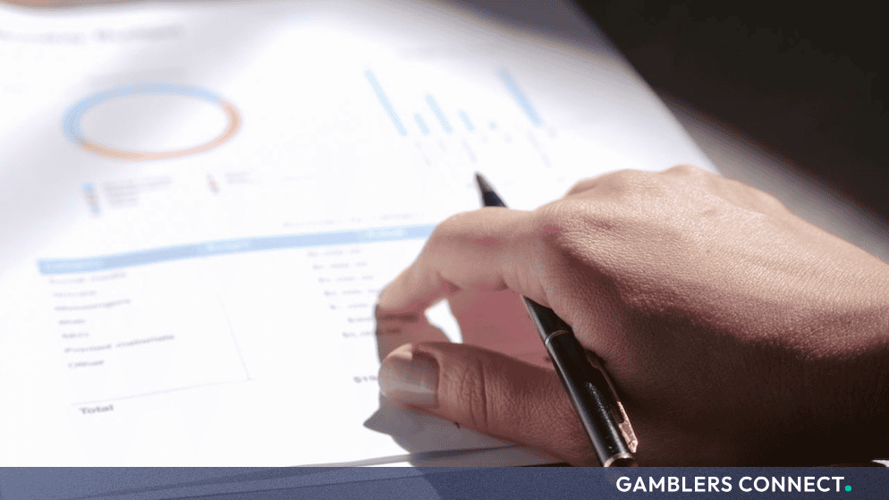 A person reviewing financial report documents and charts with a pen.