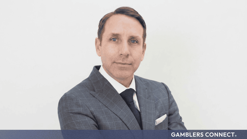 Professional headshot of Corey Goodman, newly appointed permanent CEO of NorthStar Gaming, wearing a tailored gray patterned suit and dark tie.