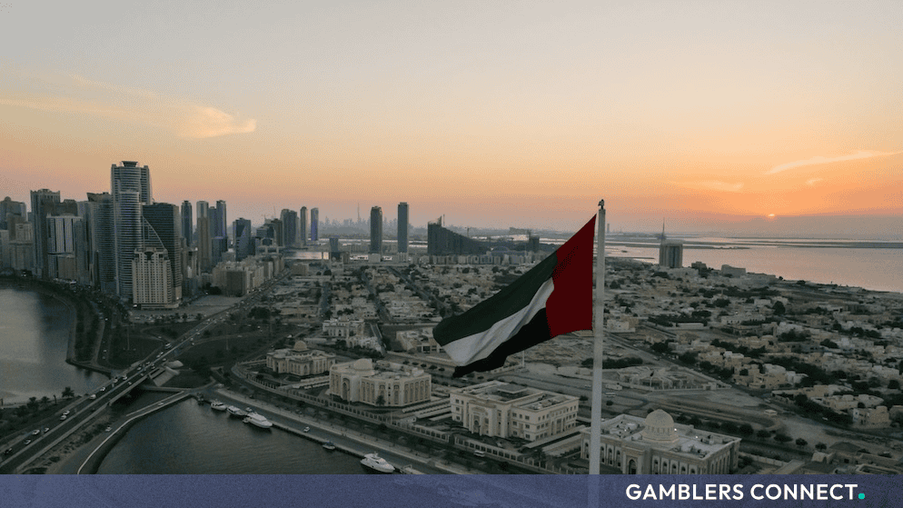 The United Arab Emirates flag flying proudly against a sunset backdrop overlooking the Abu Dhabi urban skyline and waterfront.