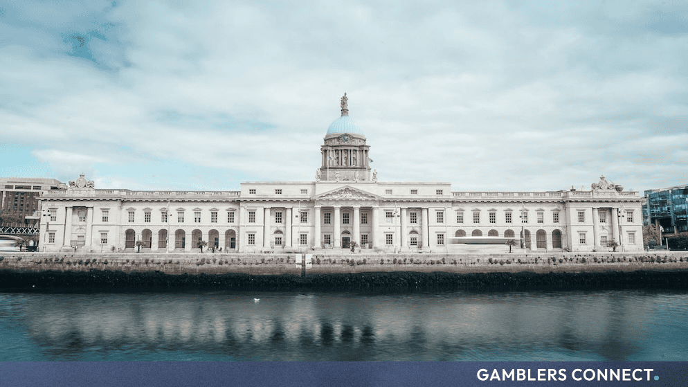 Historic government building along the riverfront in Dublin under a cloudy sky, representing Ireland's financial governance and policy centers.