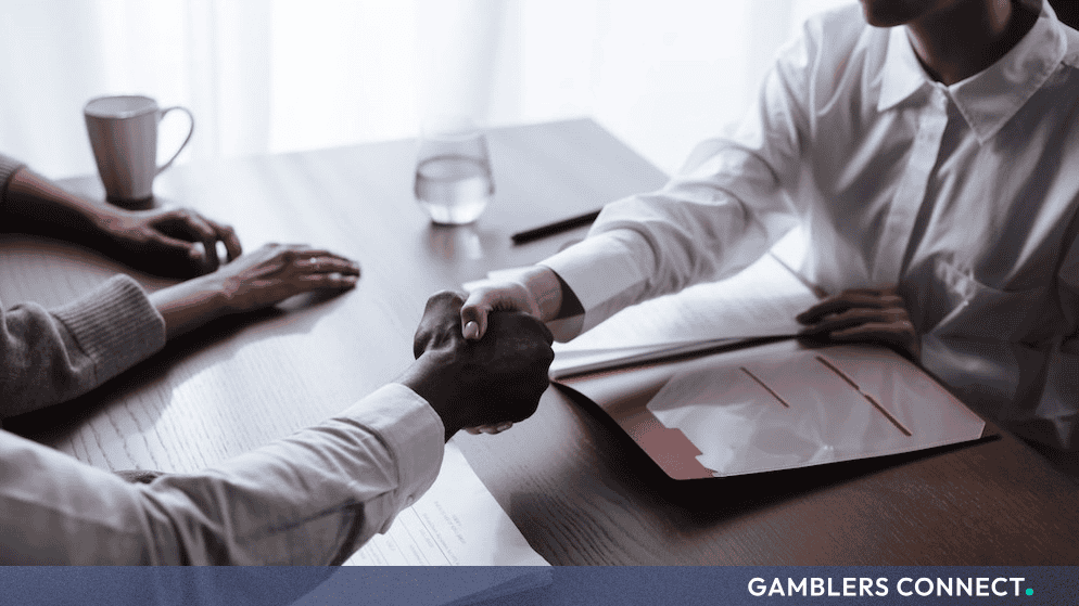 Professional business partners shaking hands across a wooden table during a contract signing.