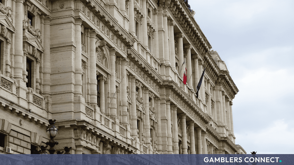 Architectural exterior view of an Italian judicial building featuring classical stone columns and hanging national flags.