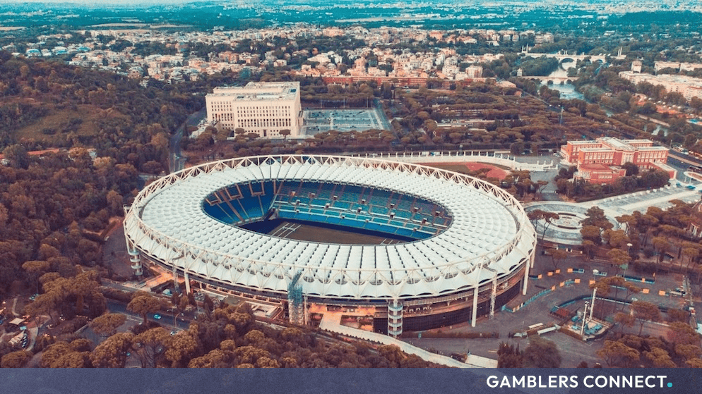 Aerial view of a large football stadium surrounded by trees and urban landscape in Rome, Italy.