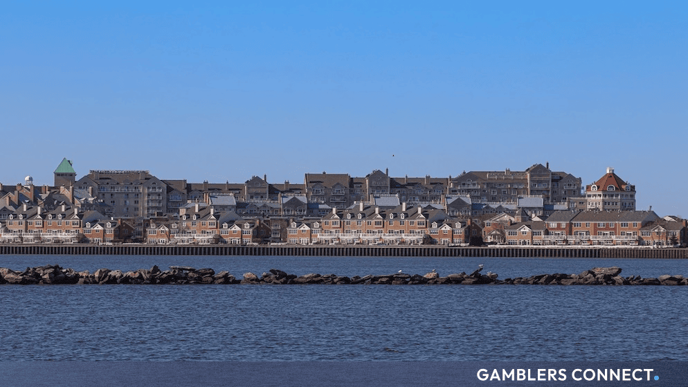 A scenic waterfront view of a developed suburban and residential town skyline along a calm riverbank in New Jersey.
