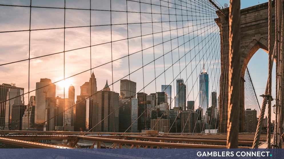 View of the New York City skyline through the suspension cables and stone arches of the Brooklyn Bridge.