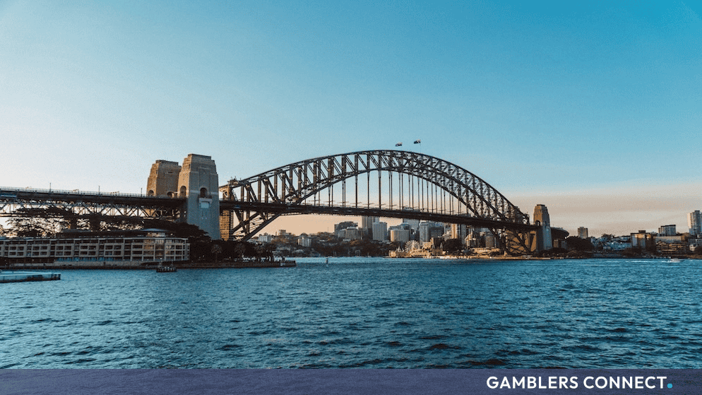 Iconic view of the Sydney Harbour Bridge against a clear blue sky over the sparkling waters of Sydney, New South Wales.