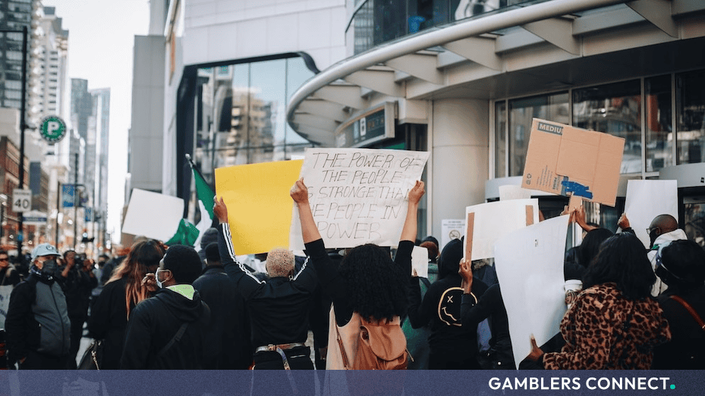 Protesters holding placards and signs during a demonstration on a city street in front of a modern building.