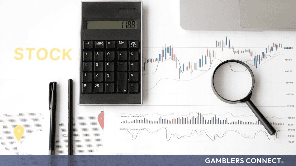 A calculator, financial charts, and a magnifying glass resting on a stock market data sheet.