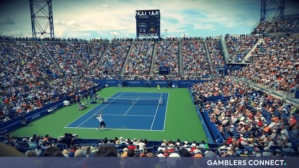 A wide-angle view of a packed tennis stadium during a major hard-court match under bright daylight.