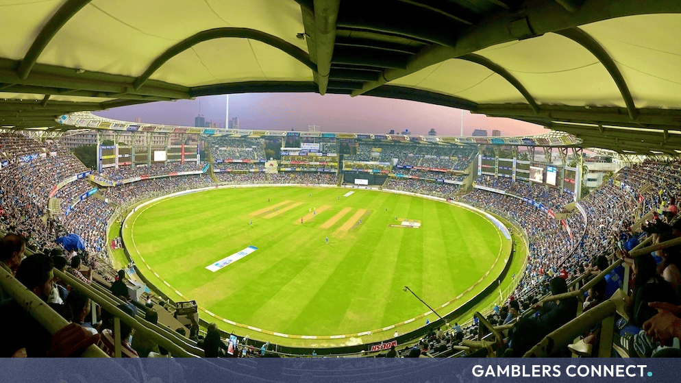 Panoramic view of a packed cricket stadium filled with spectators under a bright sky.
