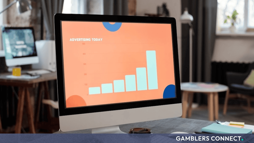 Desktop computer displaying advertising analytics charts on a wooden office desk.