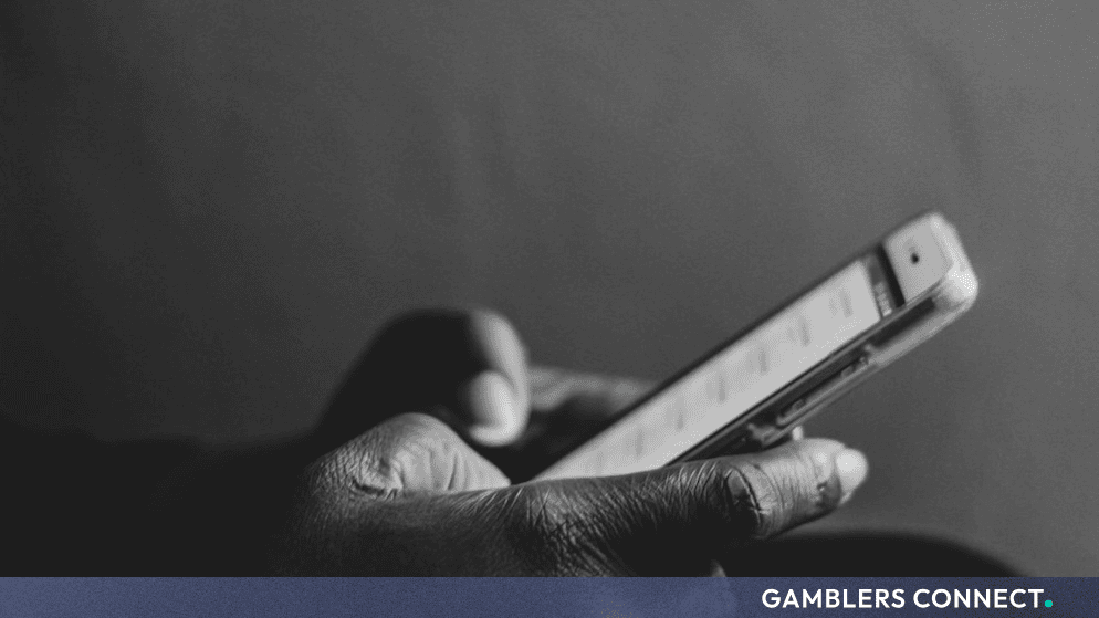Close-up of a person using a mobile smartphone device in a dimly lit environment.   