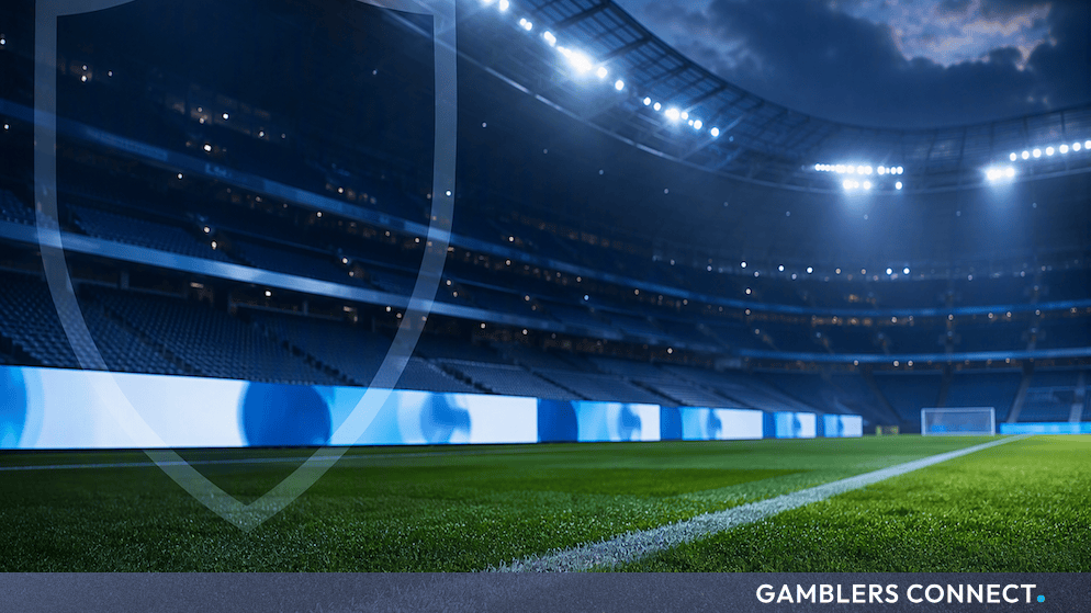 Floodlit professional football stadium pitch at night with a translucent protective shield watermark.