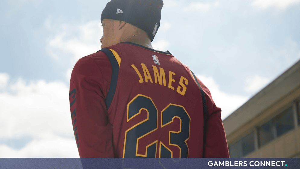 A basketball fan wearing a number 23 jersey and beanie looking out toward a sunny sky.