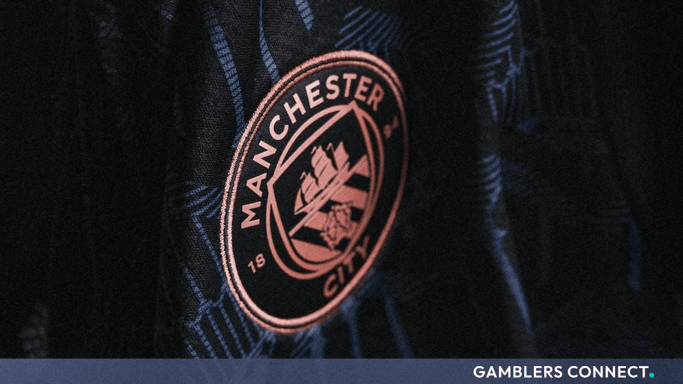 Close-up of the Manchester City football club crest embroidered on a dark textured jersey.