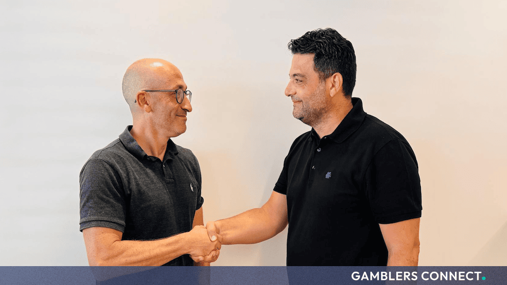 Jordan Levin and Nikos Konstakis shaking hands in a corporate office setting following OpenBet's leadership announcement.   