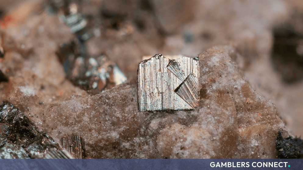 Close-up macro photograph of a metallic mineral crystal embedded in rock, symbolizing precision and structural integrity.