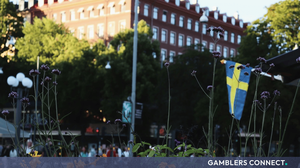 Swedish national flag fluttering outdoors in front of historic European buildings in an urban setting.