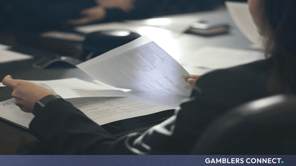 A person reviewing official regulatory documents and files in a professional office setting.
