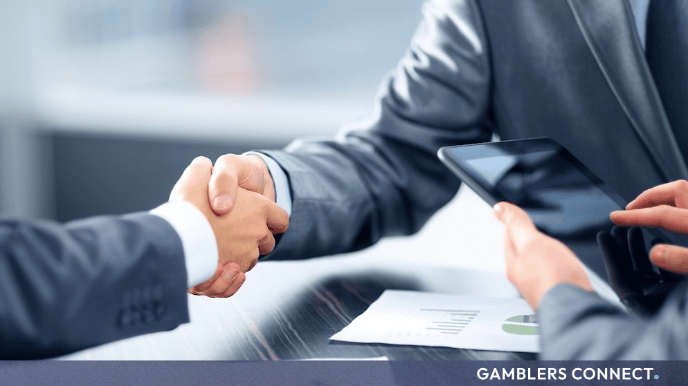 Business partners shaking hands over a financial agreement representing Honoré Gaming and ThrillTech partnership