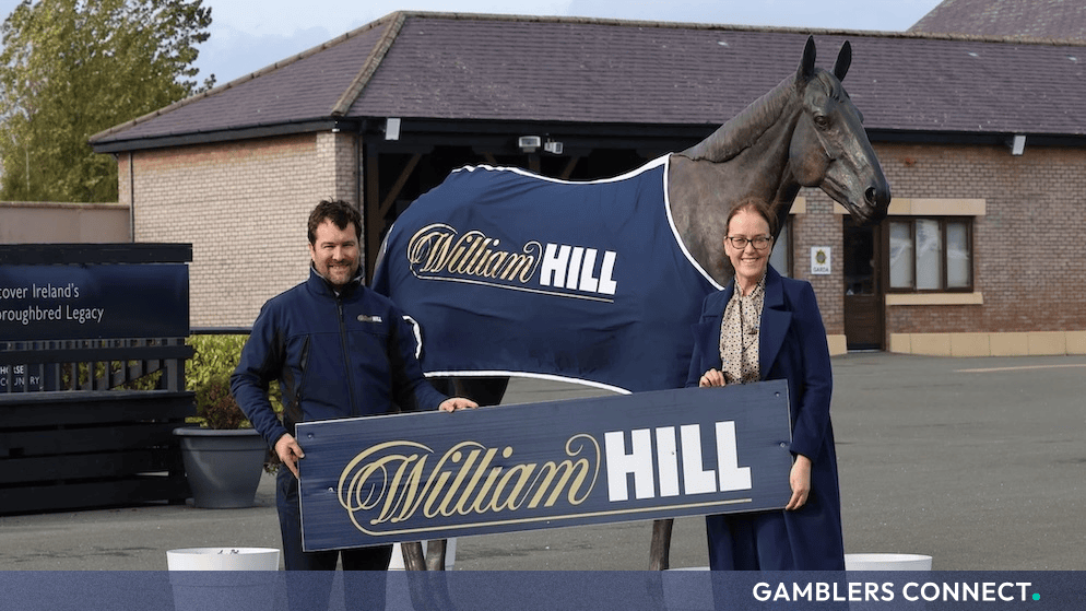 Representatives holding the William Hill branding sign in front of the Punchestown racecourse statue